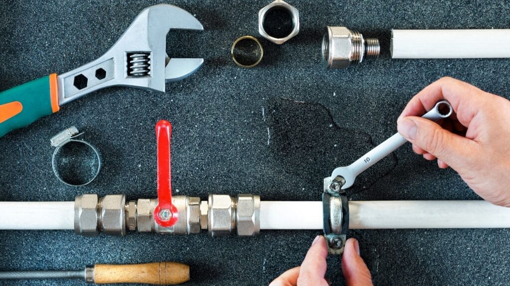 Plumber repairing a pipe valve with an adjustable wrench in Auburndale