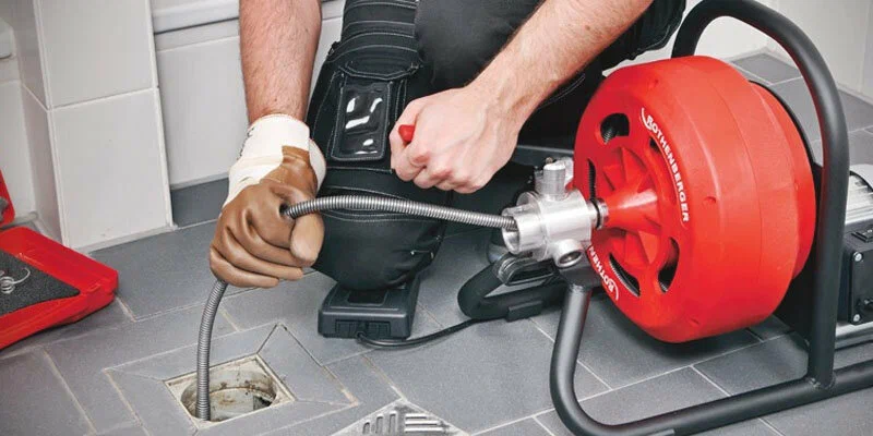 Plumber using a drain-cleaning machine in Auburndale