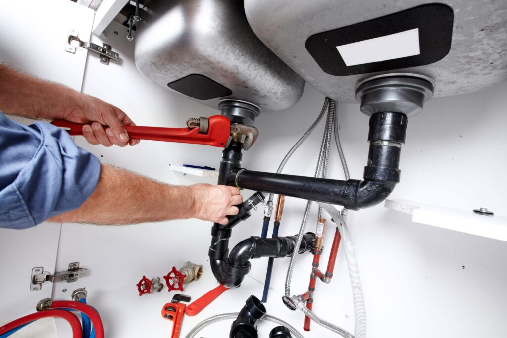 Plumber repairing drain pipes beneath a kitchen sink in Auburndale