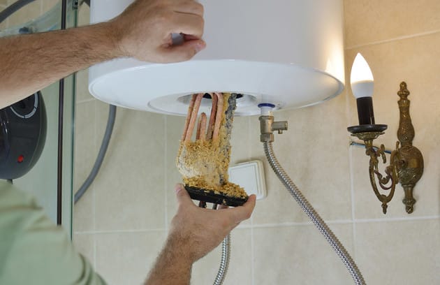 Technician removing mineral buildup from a water heater in Auburndale