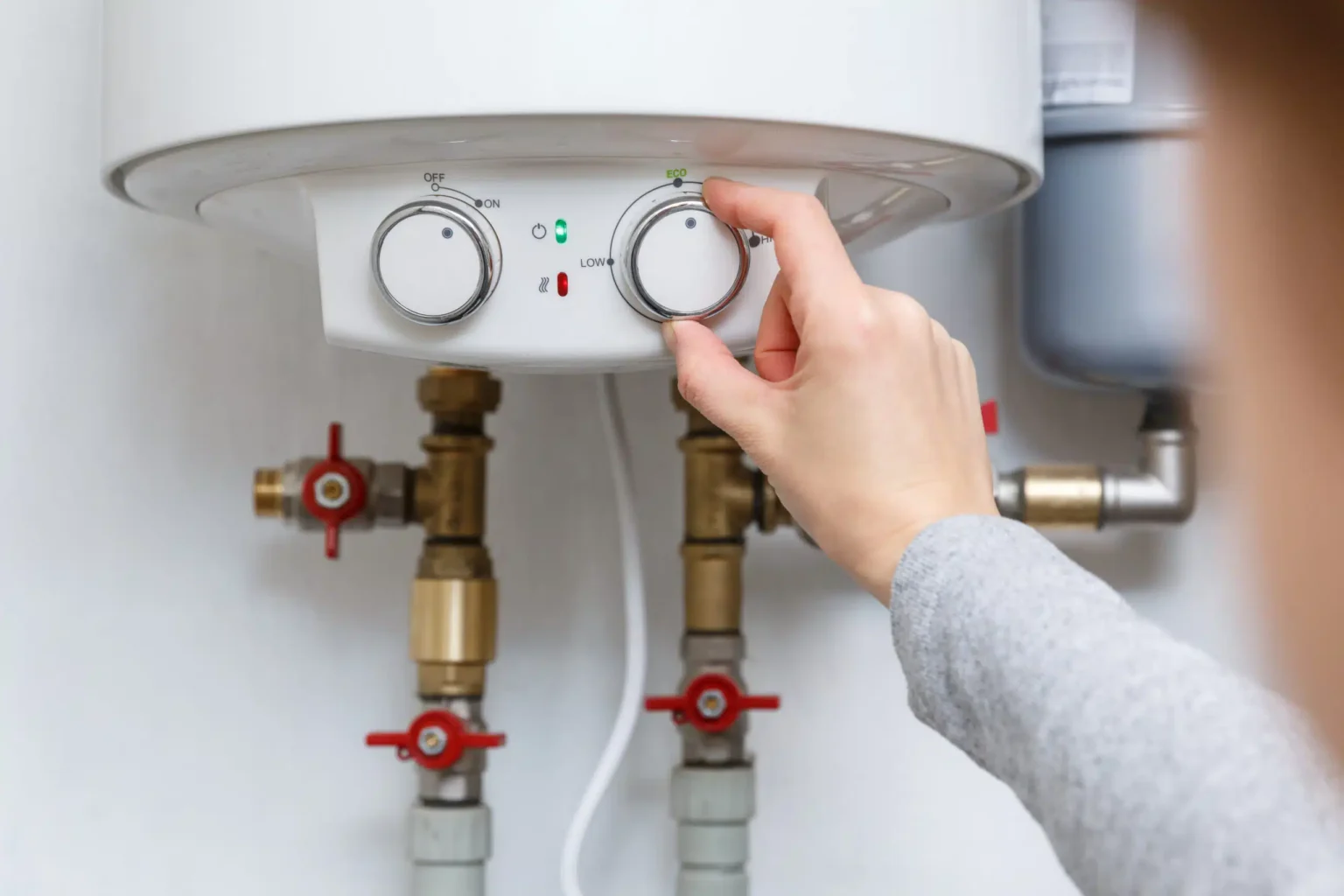 Homeowner adjusting the temperature controls on a water heater in Auburndale